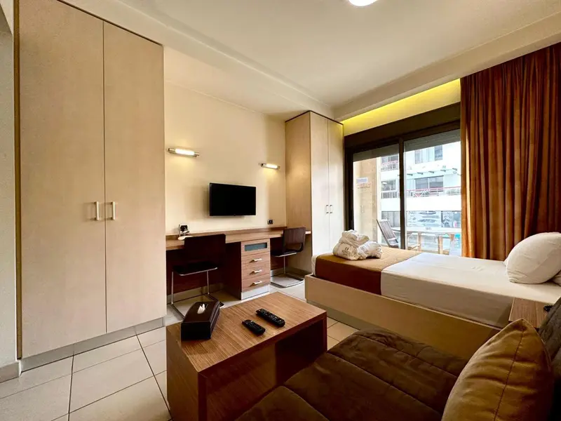 Une chambre lumineuse avec un bureau, un lit et un canapé.