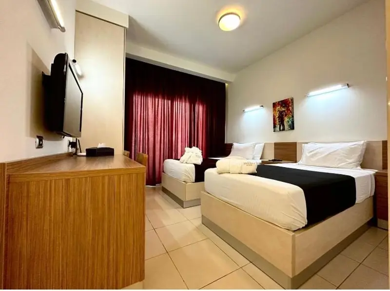 Une chambre d'hôtel moderne avec deux lits simples et un téléviseur mural.