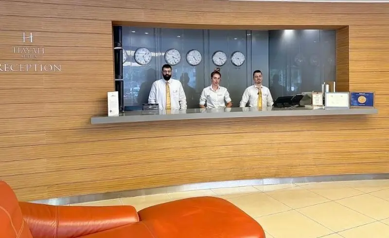 Trois employés derrière un comptoir d'accueil dans un hall d'hôtel.