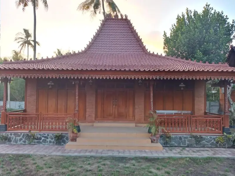 Bâtiment traditionnel en bois avec un toit en tuiles rouges et une terrasse.