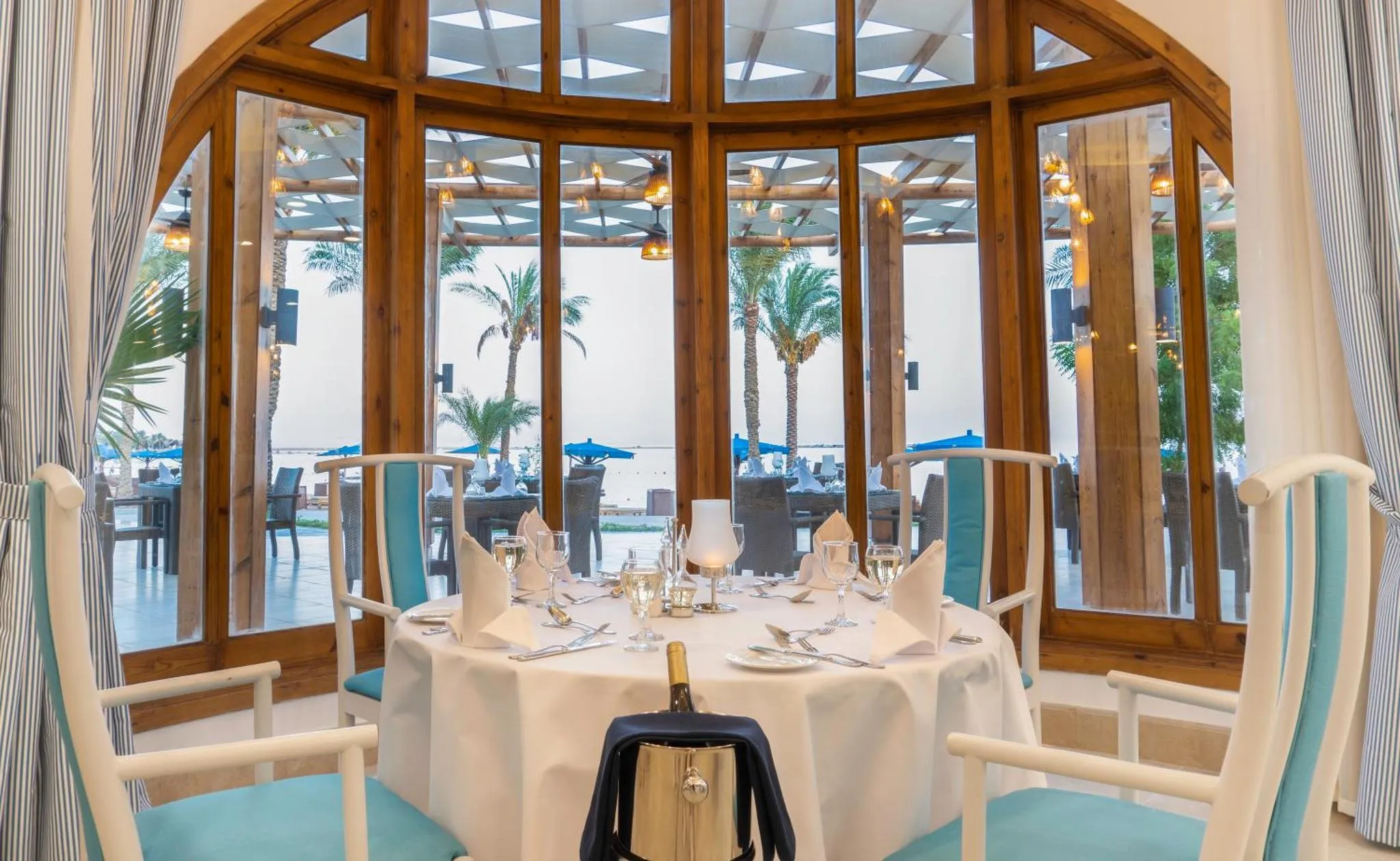Une table dressée dans une salle à manger lumineuse avec vue sur la mer.
