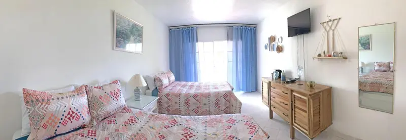 Une chambre lumineuse avec deux lits et une commode en bois.