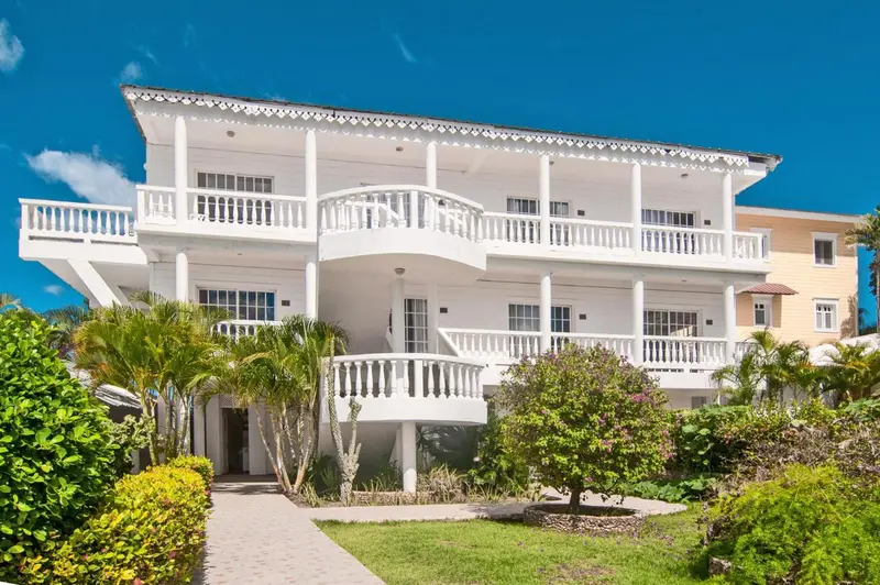 Bâtiment blanc à balcons surplombant une végétation tropicale.