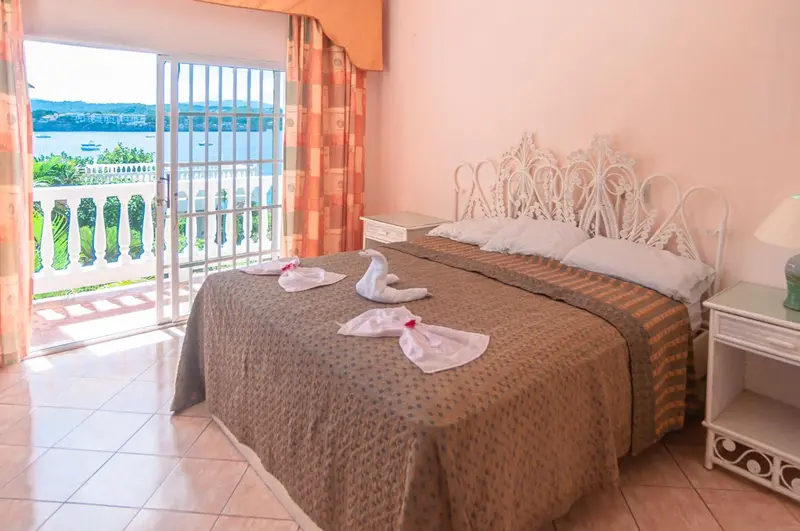 Une chambre lumineuse avec un lit décoré de fleurs et une vue sur la mer.