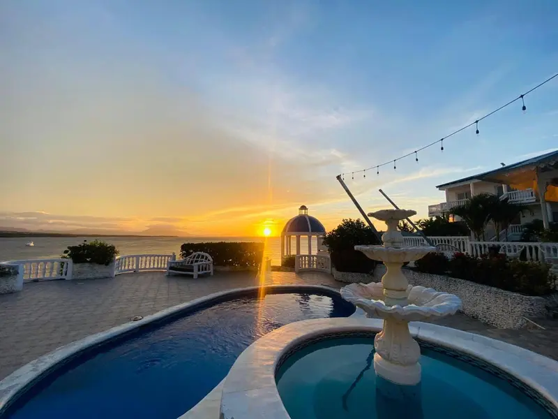 Une fontaine orne une terrasse avec piscine au coucher du soleil.