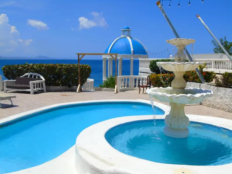 Une fontaine orne une terrasse avec piscine et vue sur la mer.