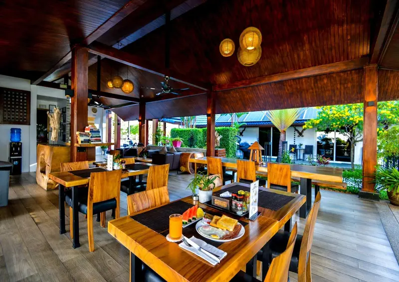 Une salle à manger extérieure avec des tables en bois et des chaises.