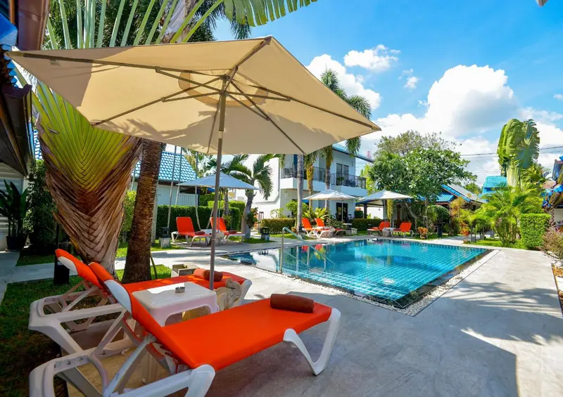 Transats orange et bleus disposés autour d'une piscine rectangulaire sous des parasols.