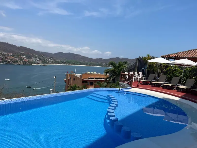 Une piscine à débordement offre une vue sur la mer et les collines environnantes.