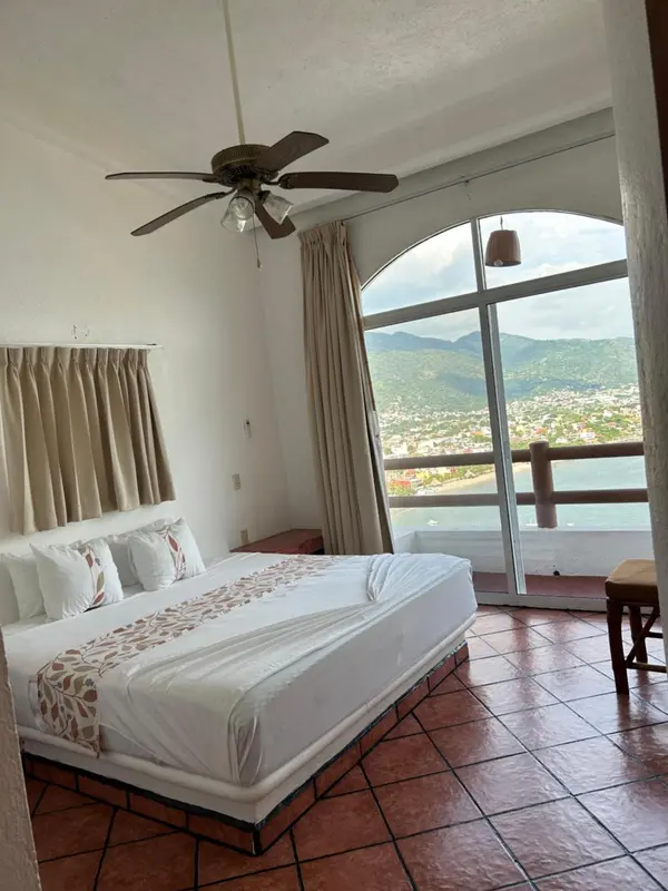 Une chambre lumineuse avec un grand lit et une vue sur la mer.