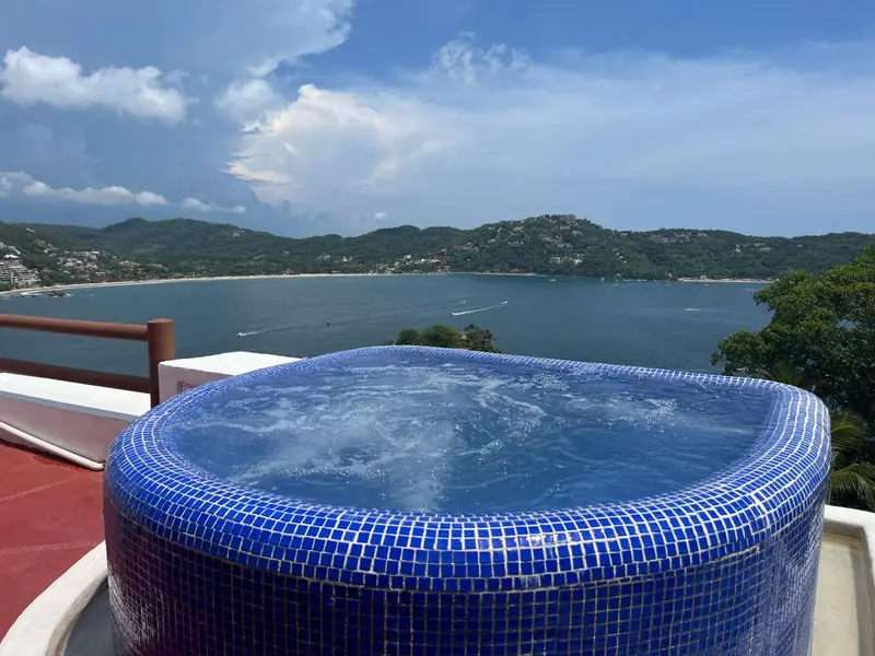 Un jacuzzi extérieur offre une vue sur la mer et les collines verdoyantes.