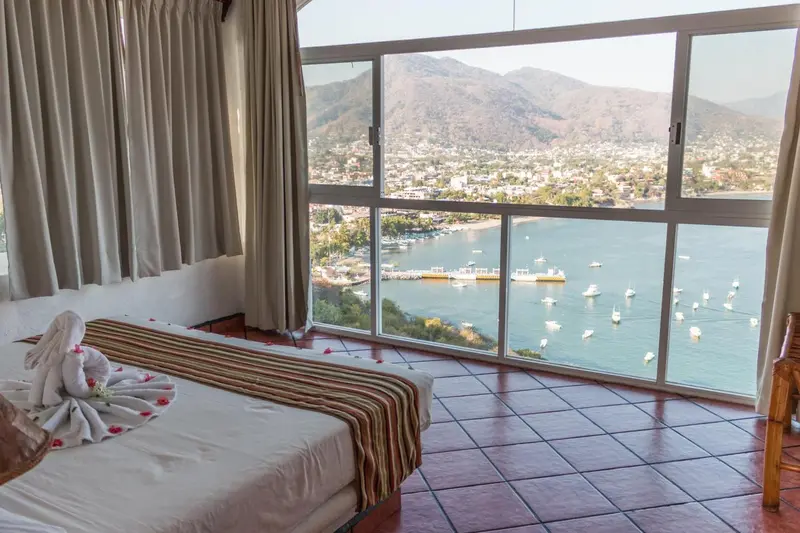 Chambre avec un lit décoré de serviettes en forme d'animaux et une vue sur la mer et les montagnes.