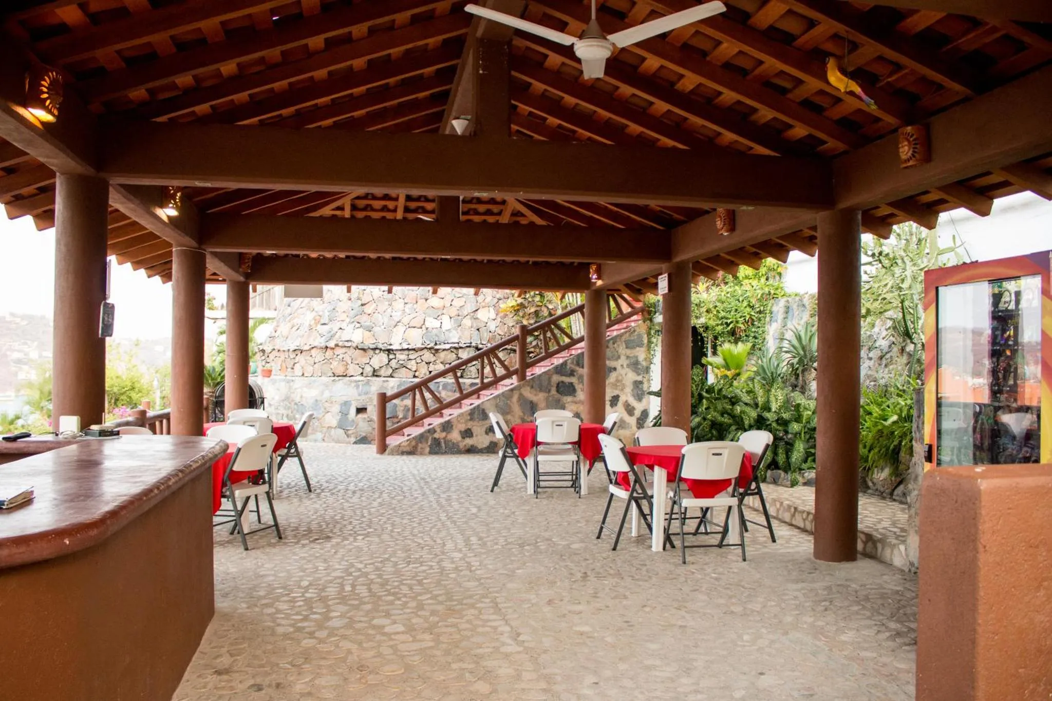 Espace extérieur couvert avec tables et chaises disposées pour les repas.