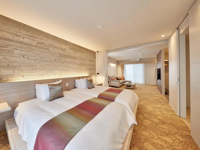 Une chambre lumineuse avec un grand lit et un espace salon.