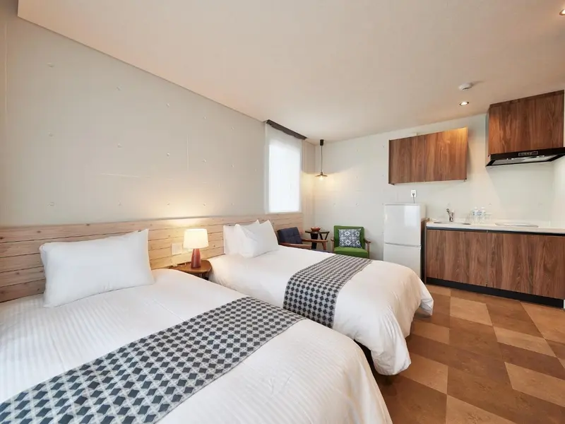 Une chambre lumineuse avec deux lits et une kitchenette.