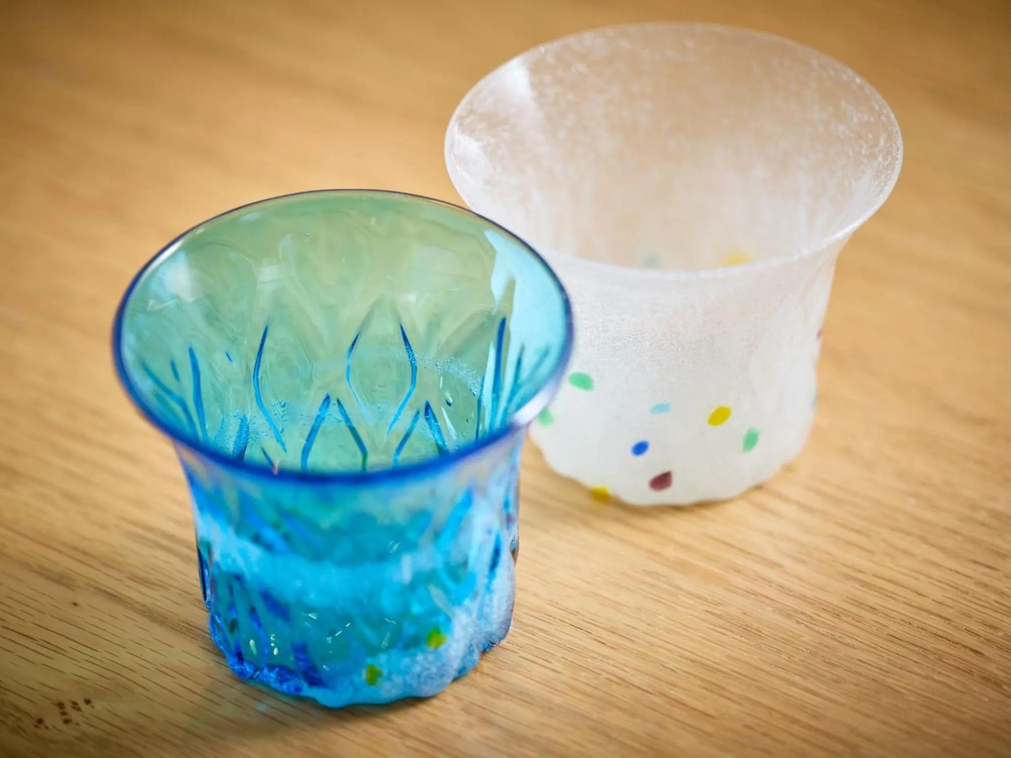 Deux verres en verre coloré reposent sur une surface en bois.