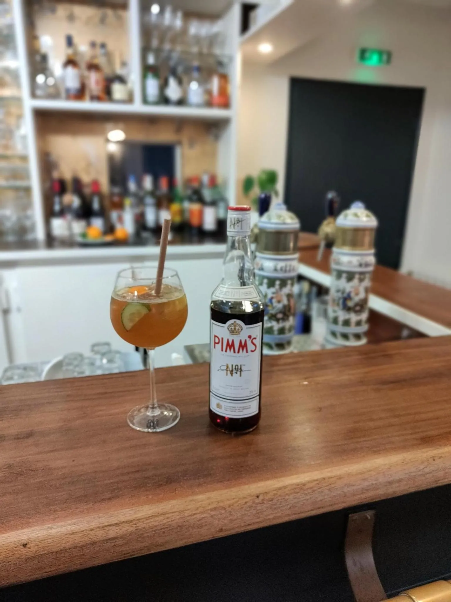 Un cocktail et une bouteille de Pimm's sont posés sur un comptoir de bar en bois.