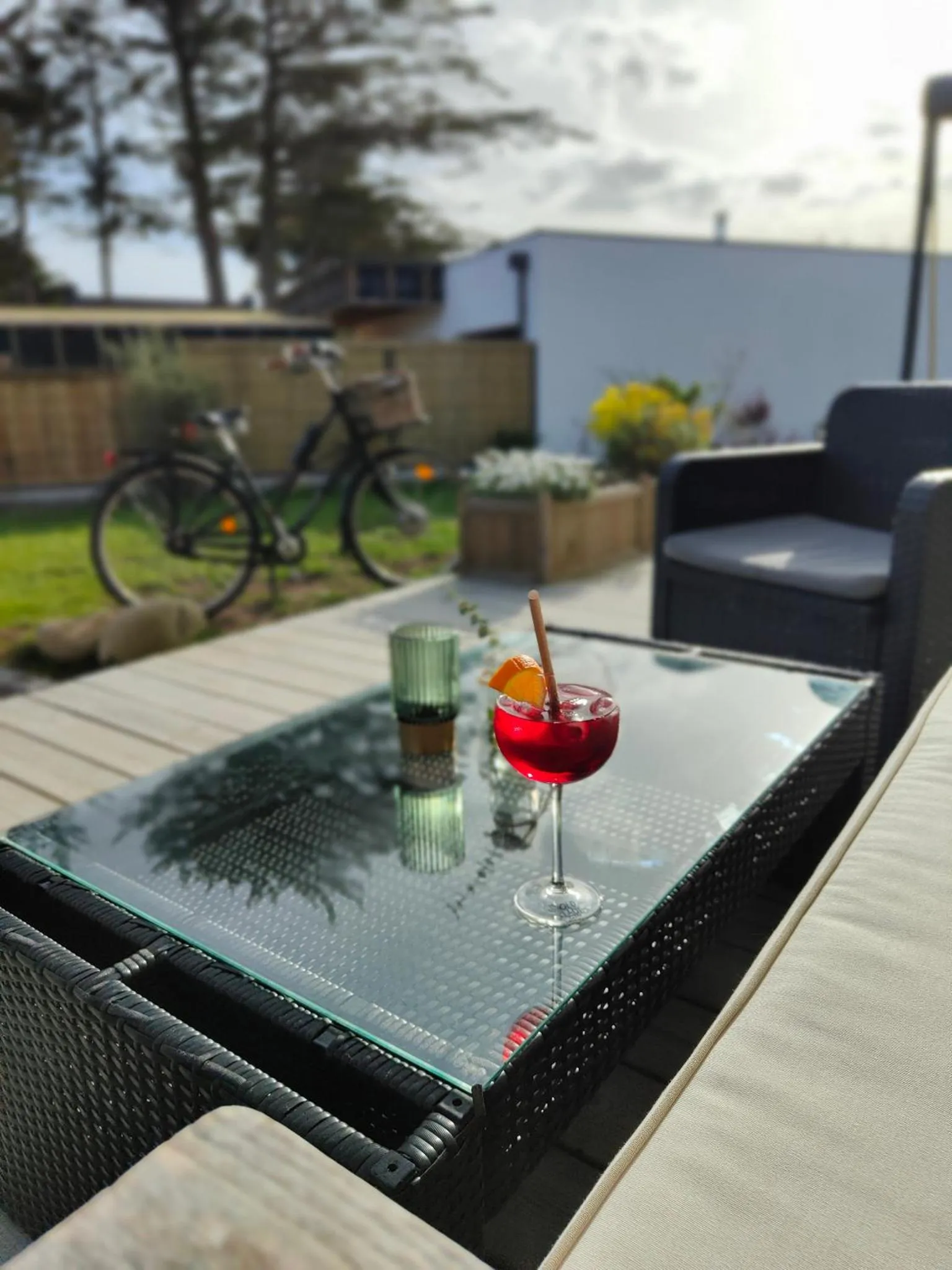 Une table basse avec un cocktail est mise en scène sur une terrasse aménagée.