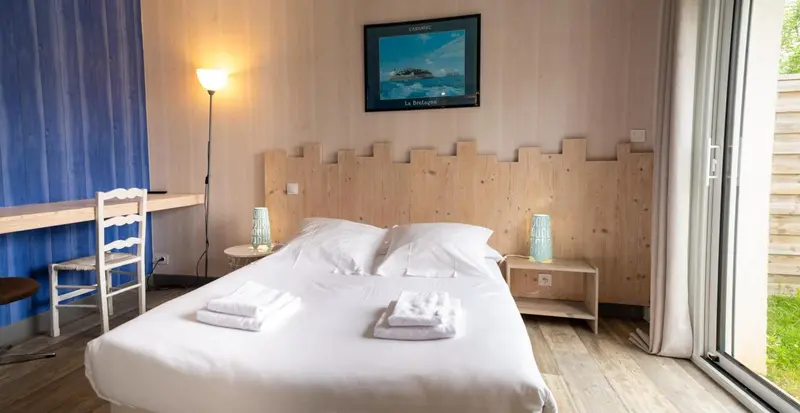 Une chambre lumineuse avec un lit double et un bureau.