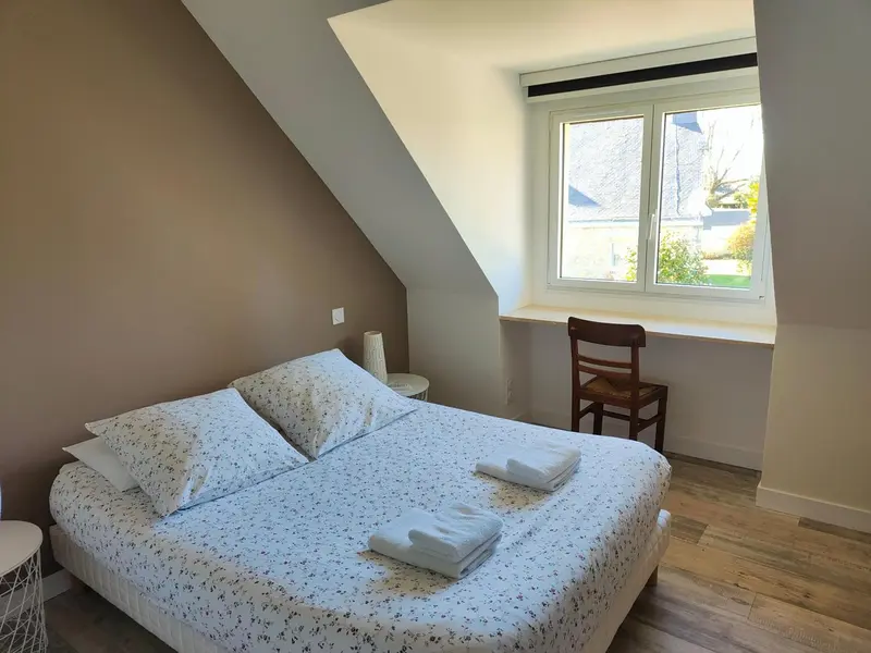 Une chambre lumineuse avec un lit recouvert d'une courtepointe à motifs et une fenêtre donnant sur l'extérieur.