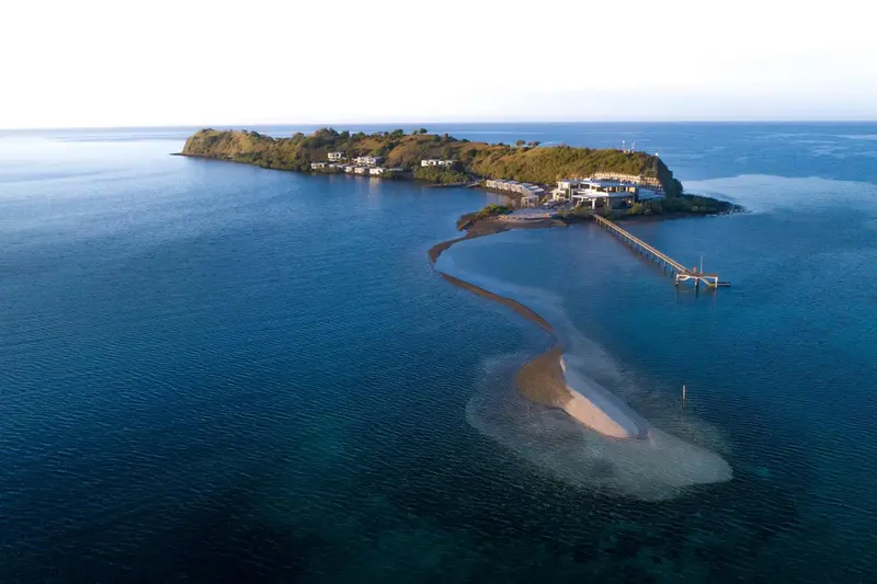 Vue aérienne d'une île reliée à la terre par une bande de sable.
