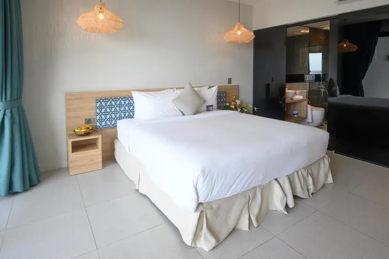 Une chambre lumineuse avec un grand lit recouvert de draps blancs.