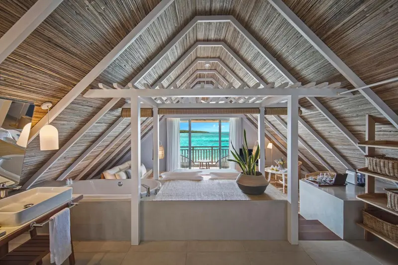 Une chambre mansardée lumineuse offre une vue sur la mer turquoise.