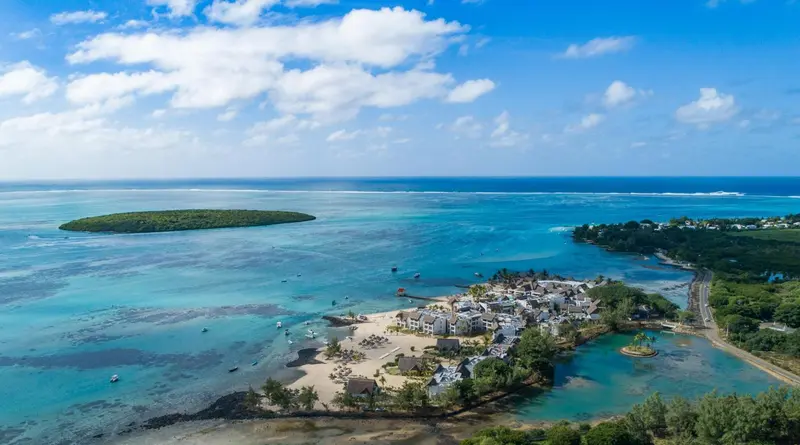 Vue aérienne d'une côte tropicale avec une île et des bâtiments blancs.