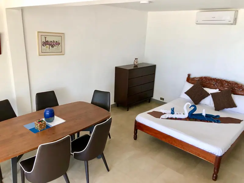 Une chambre avec un coin repas et un lit décoré de serviettes en forme de cygnes.