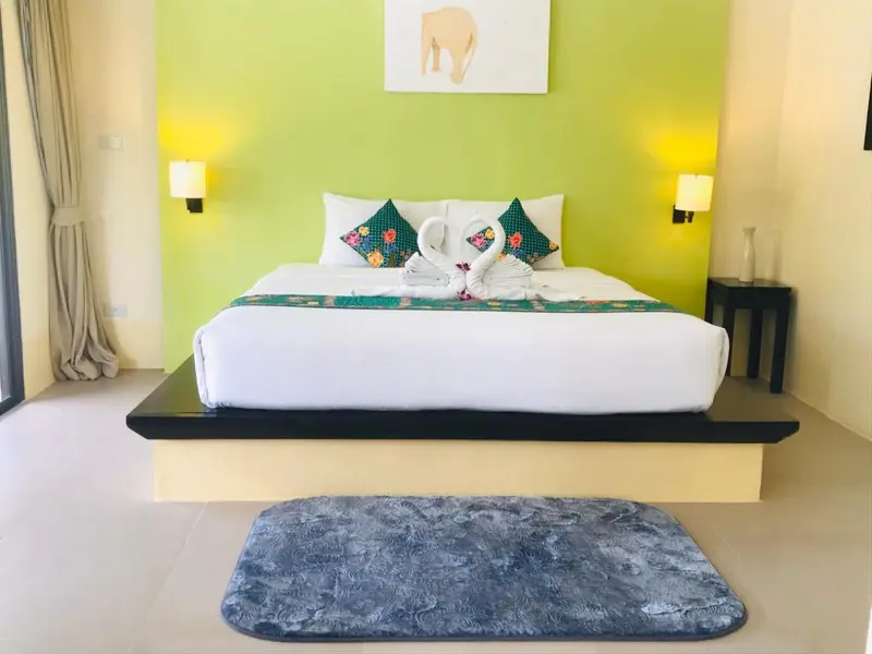 Une chambre lumineuse avec un grand lit décoré de serviettes en forme de cygnes.