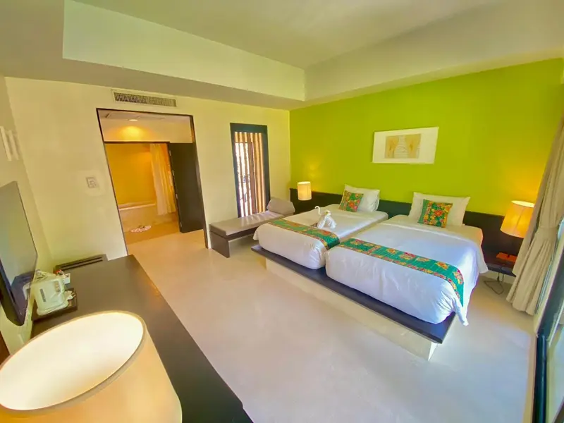 Chambre lumineuse avec deux lits simples et décoration colorée.