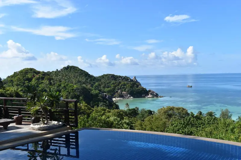 Vue panoramique sur une crique et la mer depuis une piscine à débordement.