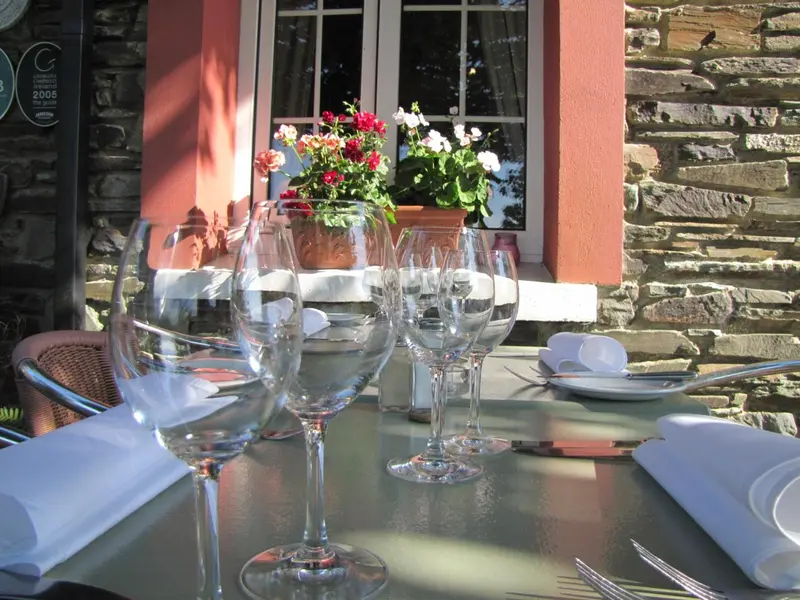 Table dressée avec des verres à vin et des couverts sur une terrasse ensoleillée.
