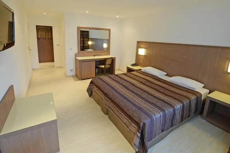 Une chambre lumineuse avec un grand lit et un espace bureau.