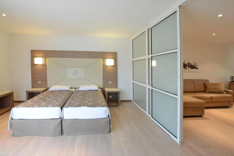 Une chambre lumineuse avec deux lits simples et un canapé.