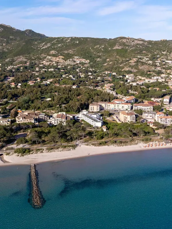 Vue aérienne d'un complexe hôtelier bordant une plage de sable fin et une mer turquoise.