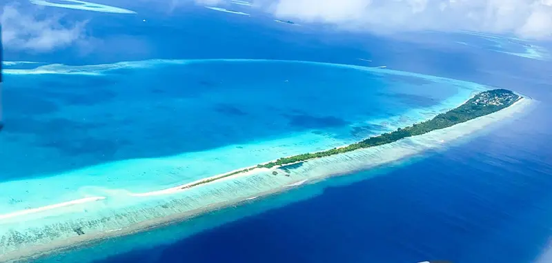Vue aérienne d'une île tropicale bordée de plages et de végétation luxuriante.