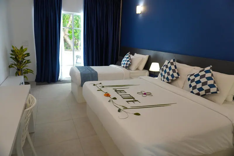 Chambre lumineuse avec deux lits simples et décoration florale sur le lit.