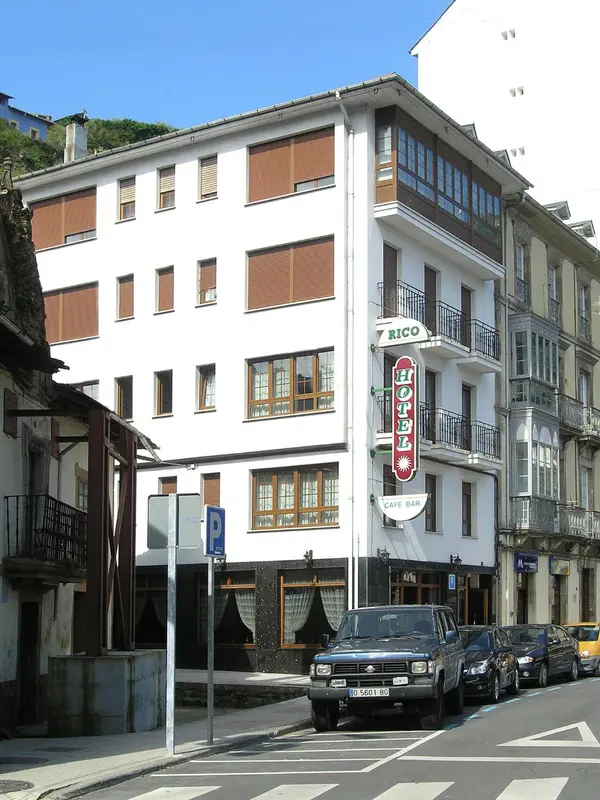 Façade d'un bâtiment blanc avec des fenêtres et un café bar au rez-de-chaussée.