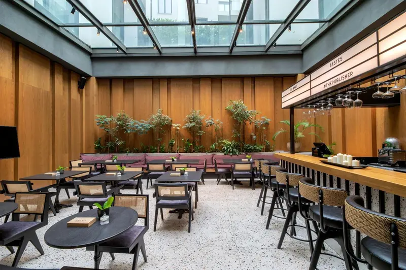 Une salle lumineuse avec des tables, des chaises et un comptoir de bar.