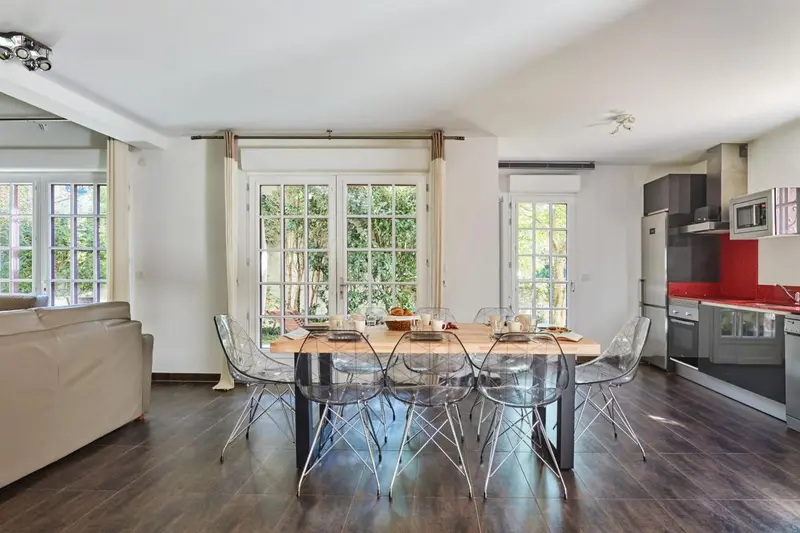 Une salle à manger lumineuse s'ouvre sur une cuisine moderne.