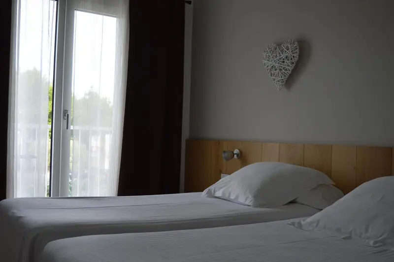 Une chambre lumineuse avec un lit blanc et une décoration murale en forme de cœur.