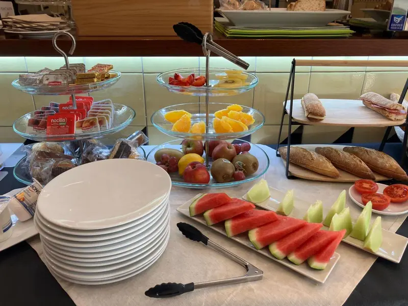 Présentation de viennoiseries, fruits frais et sandwichs sur un buffet.
