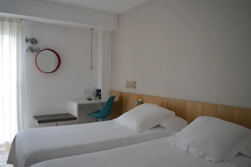 Une chambre lumineuse avec un lit blanc et un bureau.