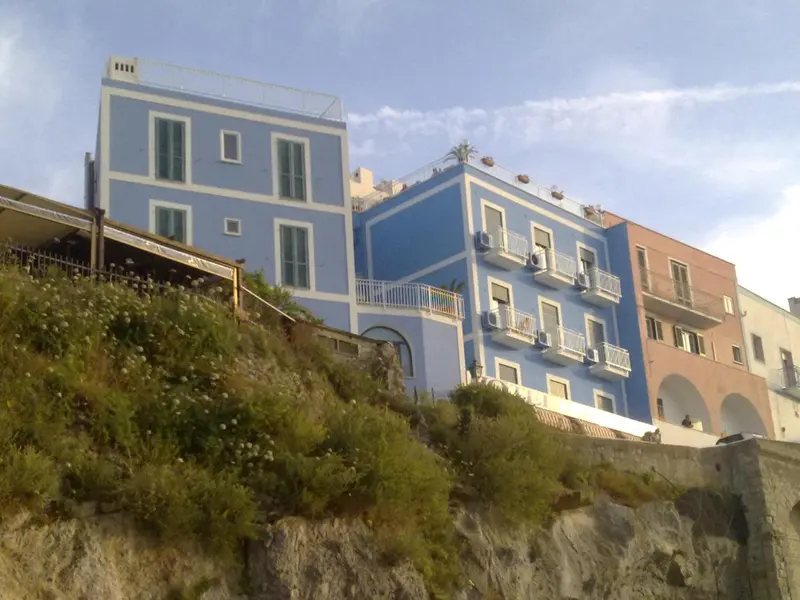 Bâtiments colorés sur une colline verdoyante avec vue sur la mer.