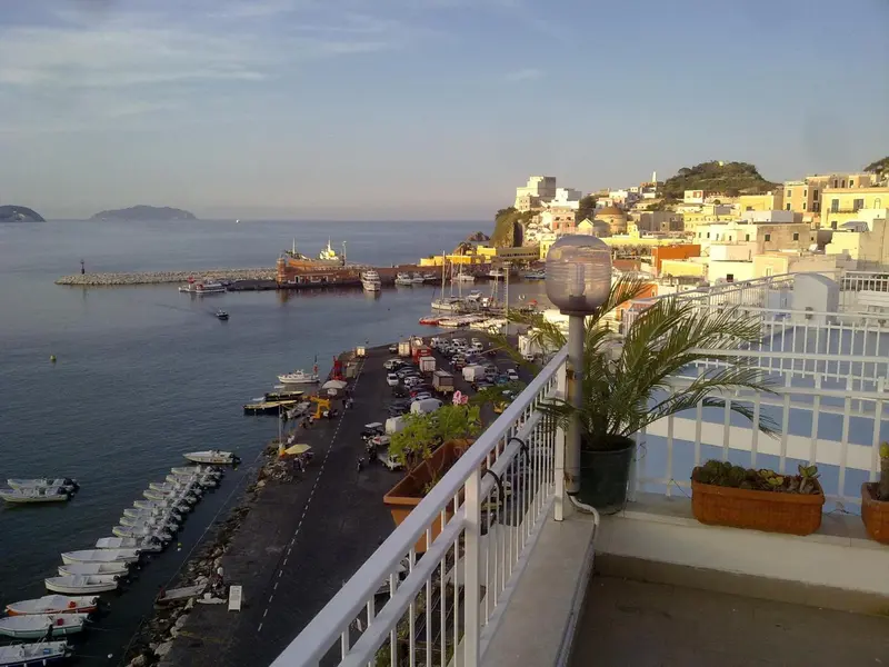 Vue panoramique sur un port de plaisance et une ville côtière au coucher du soleil.