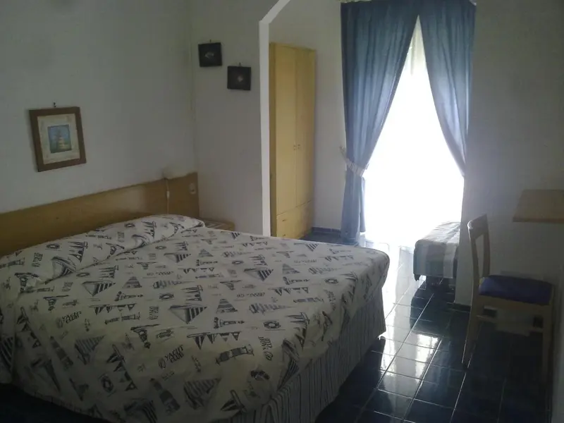 Une chambre lumineuse avec un grand lit recouvert d'une courtepointe à motifs.