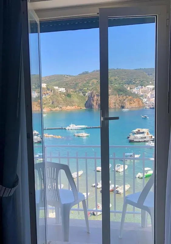 Vue sur une baie depuis une terrasse avec des fauteuils blancs.