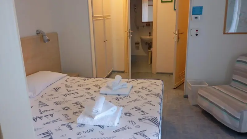 Une chambre avec un lit fait et une salle de bain visible au fond.