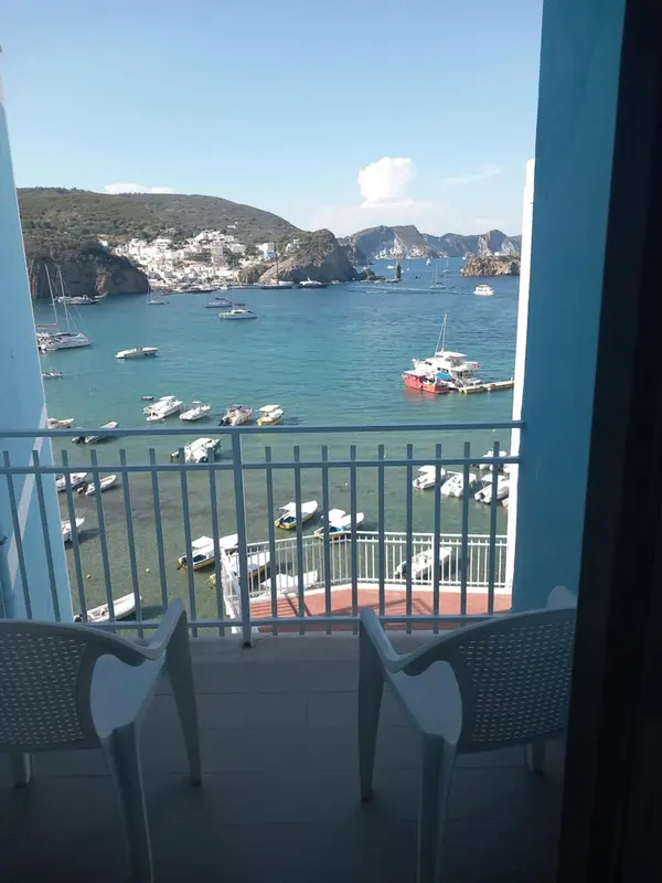 Vue sur une baie ensoleillée depuis un balcon avec mobilier d'extérieur.